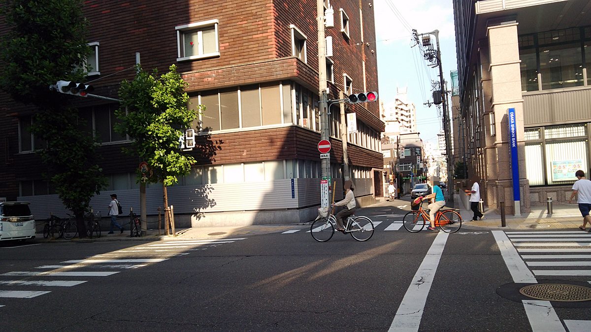 向かってくる方向の道のみが青信号。左右の道路は赤信号ながらも、自転車は信号無視して横断中