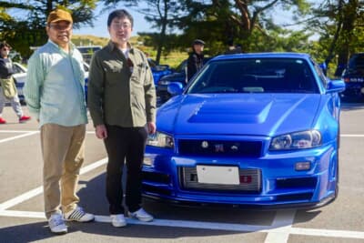 R34型GT-Rを楽しむ親子。愛車内のバイザーにはR33型とR34型の主管を務めた渡邉衡三氏のサイン入り