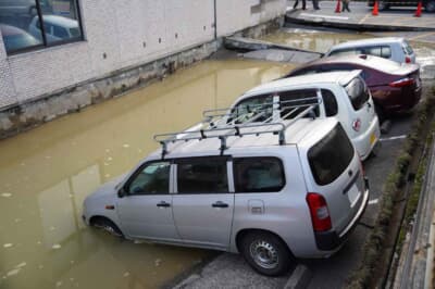 陥没した地面と、あふれた地下水に飲み込まれる車両たち