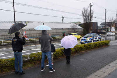 沿道には雨にもかかわらず、傘を差しながら手を振る観客も。これにラリー参加者もパッシングなどで応えていた