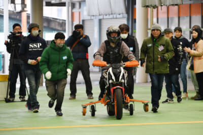 転倒を防止するためのアウトリガーを装着した中型バイクに乗車し、まずはエンジンを掛けずにボランティアスタッフの手押しから走行を始め、まっすぐ走れるようになったらエンジンを掛けて走行となる