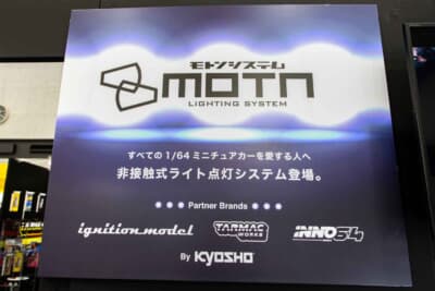 モトン ライティング システム：京商が開発中の非接触式LED点灯システムは、MOTN非接触式給電ベースにMOTN対応の1/64スケール ミニチュアモデルを搭載することでヘッドライトやリアライトを点灯させることが可能