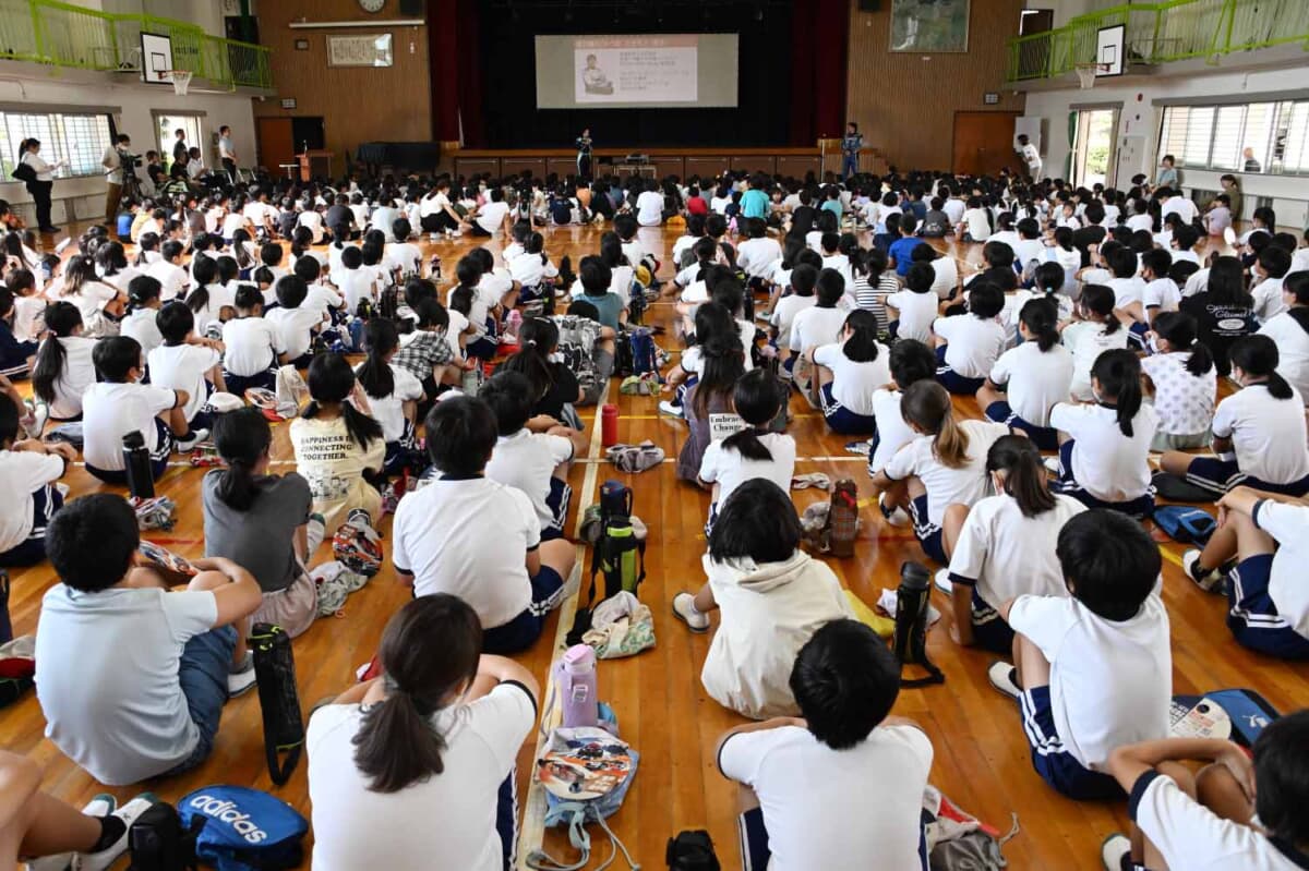 ラリーについての興味を深めるために開催されるラリー講座。今回は全校児童を集めて体育館で開催となった