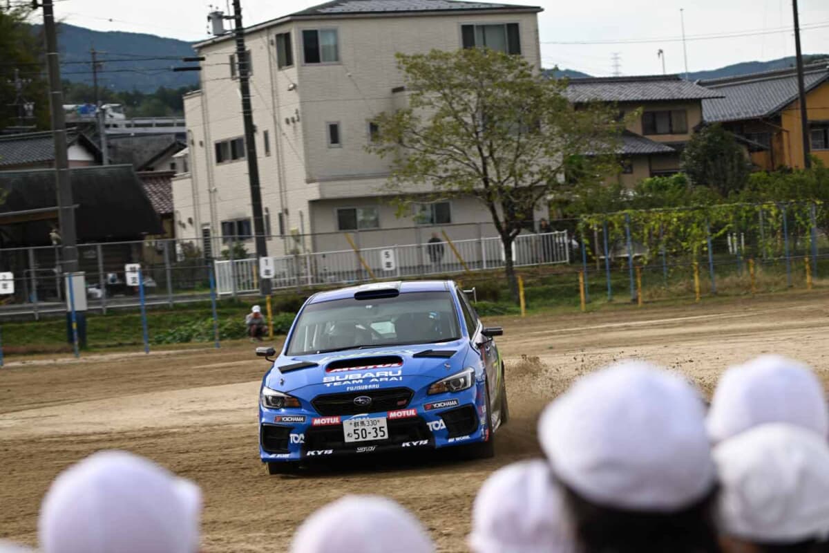 本物のラリーカーがやってくる、ということで近隣住民や父兄なども学校へ赴いてその走りを観察しているシーンも多数