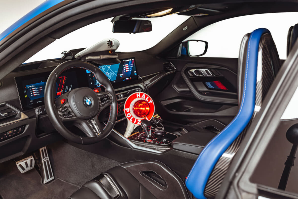 POLICE BMW M2 by AC シュニッツァー：ノーマルよりも大きなアルミニウム製のシフトパドルや、やはりアルミ製のペダル類やフットレスト、キーホルダー、iDriveコントローラーのアルミニウム製カバーなどを装着