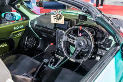 LB-nation DAIHATSU COPEN GT-K type.2：ステアリングはシリアルナンバーが入るリバティーウォークオリジナルのディープコーンをチョイス。メーターパネルにはDefiのスポーツディスプレイを設置している