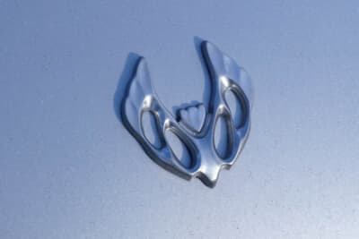 ユーノス ロードスター：NAの開発に大きく関わったデザイナー、故・田中俊治氏の手によるエンブレムを装着した前田さんの愛車。当初はデビュー時に採用を想定されるも、ユーノスチャンネルでの発売によって「Vマーク」が本採用となったという、幻のエンブレムである