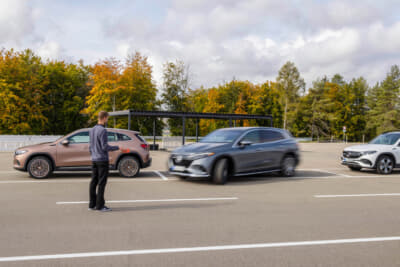 リモートパーキングアシストは、ドライバーが車外にいる間もスマートフォンを使って近くから車両を駐車・駐車解除できる機能。これにより、出入り時の快適性が向上し、ドアを開ける際の損傷から保護。写真は縦列駐車するEQ車両