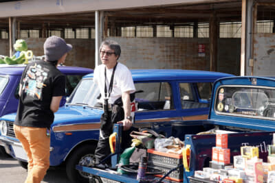 オースティン ミニ ピックアップ：筑波サーキットの走行を終えた鈴木さんの第2ラウンドは、Bパドックでのミニ カーブーツ ミーティング。ピックアップの荷室に持ち寄ったアイテムを並べて接客中