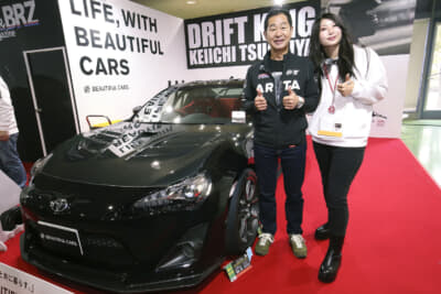 大阪オートメッセ2025のXaCARブースに展示されていた、ドリキンこと土屋圭市さんのトヨタ・86の前で当人と佐藤さんの2ショット撮影