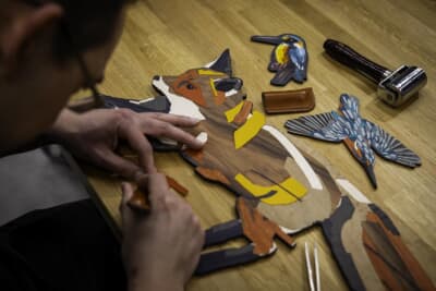 キツネが静かに森へ足を踏み入れる様子が、精緻な寄木細工で表現されている