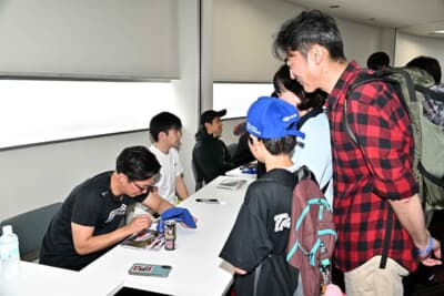 お目当てのドライバーにお気に入りのグッズにサインしてもらうことも可能。スーパーGTでスバルのリザーブドライバーを努める奥本選手の前にはスバルファンも訪れた