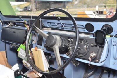 日産 2代目 パトロール:2本スポークのステアリング。トランスファーの切り替えとハイ&ローギア、3速MTの3本のレバーがある