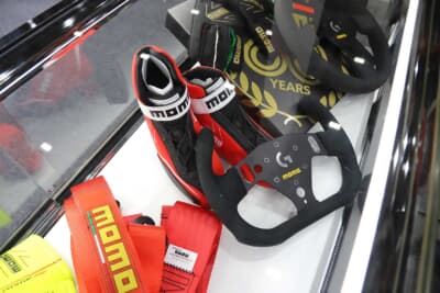 競技専用ステアリングやレーシングシューズ、シートベルトなどのアイテムを展示