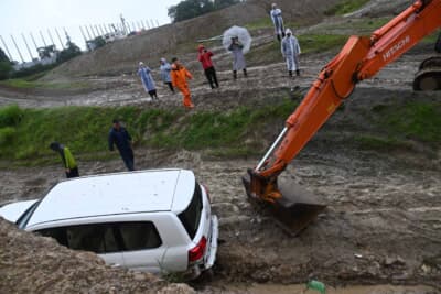 泥濘地でスタックしてしまったトヨタ ランドクルーザーを重機が引き上げる