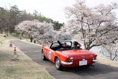 アートビレッジ明神池の周回路を使ってのPC競技をする参加車両たち、今回は桜がピークということもあり希少なヒストリックカーと桜の写真を収めようという見学客も多いポイントであった