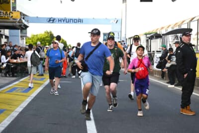 お目当てのドライバーやチームにサインをもらうために、列の先頭を目指してダッシュするファンたち