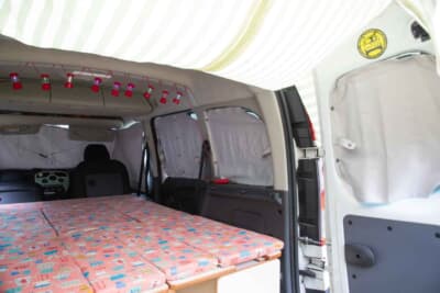 ルノー カングー：ホワイトハウスオリジナルカーテンでしっかり遮光。お手製のタープを装着してプライベート空間もしっかりと保てるようになっているのも、キャンピングカーメーカーならではの装備だ