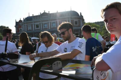 リアウィングの上でポスターにサインするドライバーたち