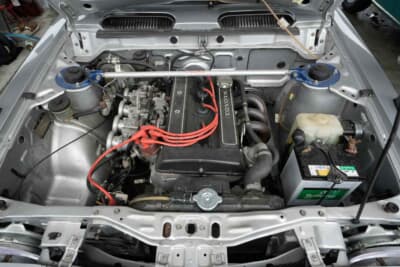 トヨタ スプリンター トレノ:クスコのタワーバー。2TG型の1.6L DOHCエンジンに付くキャブレターはファンネル仕様だが、簡単にオリジナルに戻せる。純正の鋳鉄製エキゾーストマニホールドなど、オーナーの純正主義がうかがえるエンジンルームだ