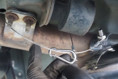 インテック・マフラーカッター:装着は純正マフラーにボルト固定するだけじゃない。脱落防止ナットが加わり、固定したボルトの一箇所に脱落防止ワイヤーを掛けるので万が一ボルトが緩んで外れてもマフラーカッターが脱落することはない