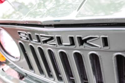 スズキ ジムニー：フロントグリルは、先代モデルの横スリットから2代目は縦8本型スリットに変更。SUZUKIの文字も抜き文字仕様である