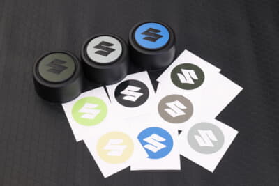 スズキ ジムニーノマド:純正ホイールキャップ用ステッカーは、ジャングルグリーン、シフォンアイボリーメタリック、ピュアホワイトパール、ブルーイッシュブラックパール、ミディアムグレー、キネティックイエロー、スペリアホワイト、ブリスクブルーメタリック、シルキーシルバーメタリックの9色を用意