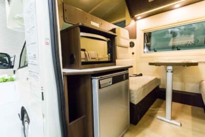 トヨタ ハイエース:左手前には冷蔵庫と電子レンジ、右手前にはシンクが設置され、その奥が5人掛けのダイネットとなっている