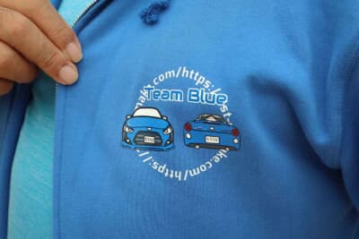 会場で着ていたパーカーもブルーで、胸には愛車のロゴが入っている