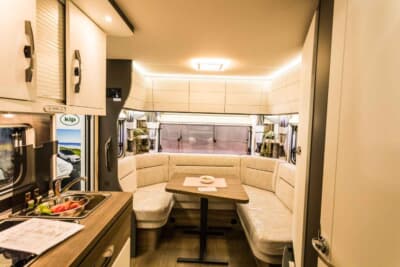 495UL エクセレント エディション：車体右側面の後方に設置されたドアから車内に入ってみると、コの字型に配されたソファと木製テーブルが目に飛び込んでくる