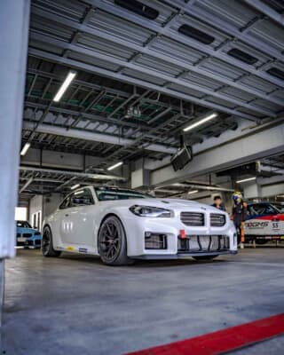 BMW M2 CS Racing ： 迫力のフロントマスク。冷却効率を極限まで高めた大型エアインテークと専用リップスポイラーが、レーシングカーならではの機能美と力強さを主張している