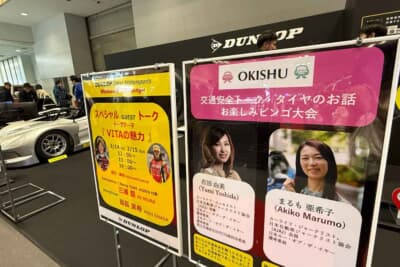 OKISHU×ダンロップブース：ブース前に設置された案内パネル。豪華ゲスト陣による交通安全トークショーのスケジュールが告知されている