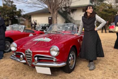アルファ ロメオ ジュリエッタスパイダー: 美しいオープンカーの傍らに立つ吉田由美。旧車特有のエレガントな佇まいは、現代のクルマにはない特別な色気を放ち、時代を超えて多くのエンスージアストを魅了する