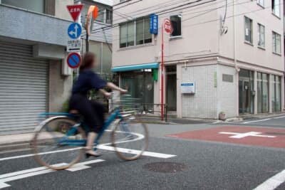 一時停止を無視して交差点へ進入する自転車のイメージ。指定場所での一時不停止は5000円の反則金が科される。クルマとの接触事故でとくに多い原因であり、自分の命を守るためにも絶対厳守のルールだ