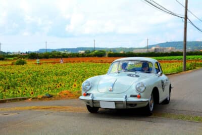 晴天に恵まれた最終日、昨今ちまたで話題の「伊計島フラワーロード」のひまわり畑に見守られつつ、カートによるユニークな最終P.C.競技ポイントへと向かう1964年式ポルシェ 356SCの父娘コンビだ