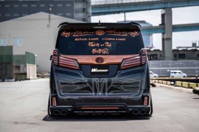 トヨタ アルファード：真後ろから捉えたスタイリング。複数ブランドのエアロパーツを違和感なくまとめ上げ、ボディ全面に施された特殊塗装のインパクトが顕著に表れるアングルだ