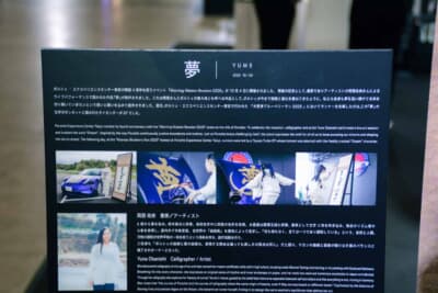 会場に設置された解説パネル。岡西氏が6歳から書を始め、ポルシェのオーナーでもあることが日本語・英語の両言語で記されている