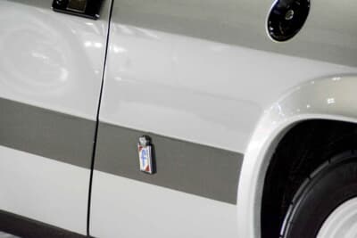 ランチア モンテカルロ：ボディサイドに配されたピニンファリーナのエンブレムと「f」バッジだ。名門カロッツェリアがデザインとコーチワークを手掛けた証が、誇らしげに輝く