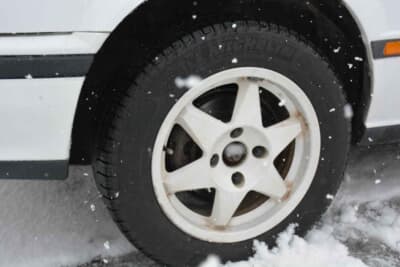 日産 ブルーバード SSS-R：雪に埋もれたフロントホイール。白い社外ホイールが装着されている