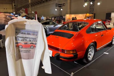 ポルシェブースに展示されたオレンジのポルシェ 911（911S）。往年のクルマとともにヘリテージグッズも並べられ、「昔と今」を同時に楽しめる展示となっていた