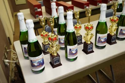 今シーズンもシャンパンのラベルには参加者のマシンが描かれる。開幕戦は昨シーズンの最高峰、1クラスを制した新関透のL275ミラ