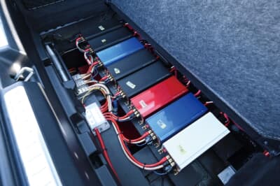 メルセデス・ベンツ EQS450＋：ラゲッジに設置されたアンプとプロセッサー類。小型モノラルアンプ「P-100」シリーズを各スピーカーに1台ずつ配置し、デジタルプロセッサーを左右独立で計2台搭載している。