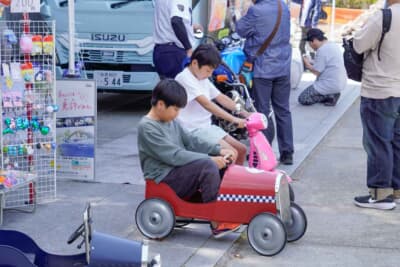 隣の縁日エリアではペダルカーが展示され、未来のドライバーたちが笑顔で楽しんでいる