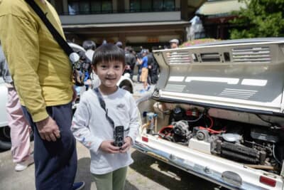 将来のドライバーたちが、ずらりと並んだ名車たちを前にカメラを構えて楽しんでいる