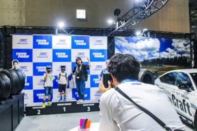 TOYO TIRES PROXES：フォトブースで親子が撮影されている様子。お子さんはペーパークラフトのフルフェイスのヘルメットを被り記念撮影に収まった