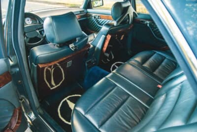 メルセデス・ベンツ 560SEL AMG 6.0-4V:スリーポインテッドスターを織り込んだフロアマットと後席のウッドトレーが上質さを際立たせる