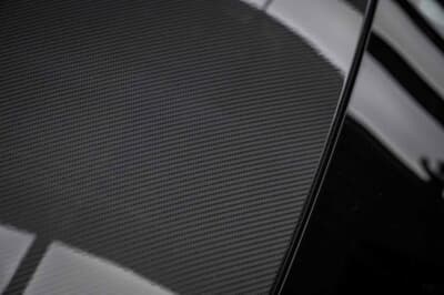 ツヤありのカーボン柄フィルムをボディに施工した質感。光沢が織り目の立体感を引き立てる