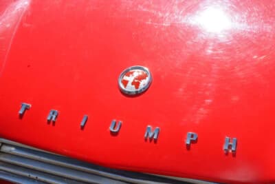 トライアンフ TR4A:真っ赤なボンネットの先端に誇らしげに輝くトライアンフのエンブレムだ