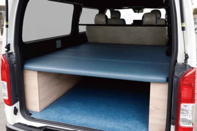 トヨタ ハイエース: 荷室には4分割ボックスベッドキットをセットしている。衣服への色移りや日焼け退色を防ぐ特殊なデニム素材を採用しており、気兼ねなく車中泊を楽しめる最高のお手本だ