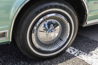 クライスラー ニューヨーカー:足回りは純正のスチールホイールにハブキャップの組み合わせだ。215/75R15という日本ではあまり見かけないサイズのホワイトリボンタイヤを装着している